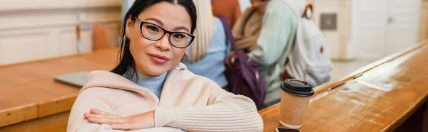 Mature asiatique étudiant en lunettes regardant caméra près de café pour aller à l'université, bannière — Photo de stock
