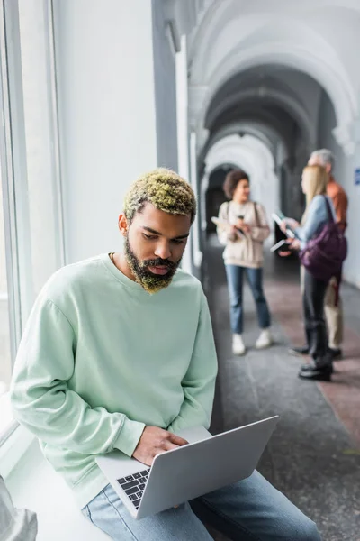 Afroamerikanische Studentin benutzt Laptop auf Fensterbank in Universität — Stockfoto