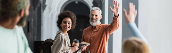 Professeur mature agitant les mains à des étudiants multiethniques flous à l'université, bannière — Photo de stock