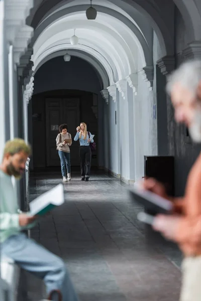 Interrassische Studenten mit Kaffee und Laptop auf dem Flur der Universität — Stockfoto