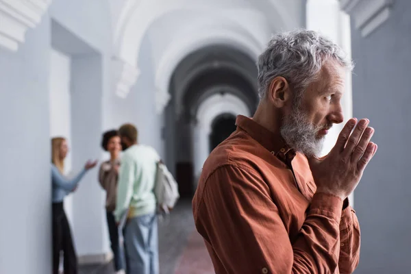 Mature teacher looking away in corridor of university — Stock Photo