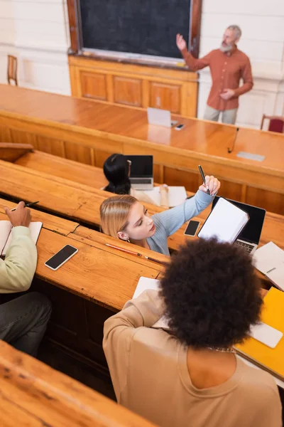 Overhead view of student holding notebook near african american friend in university auditorium — Stock Photo