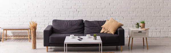 Tassen, Handy und Fernbedienung auf Couchtisch in der Nähe der heimischen Couch, Banner — Stockfoto