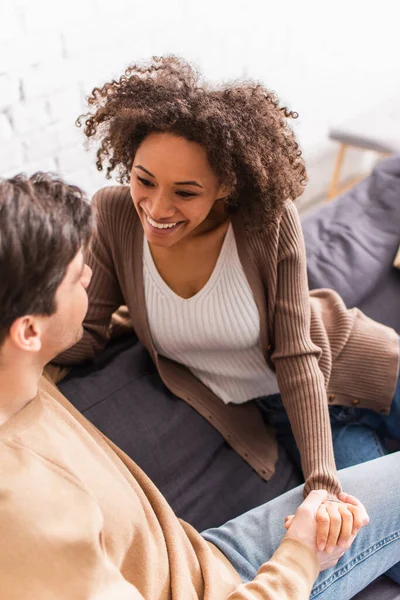 Vista ad alto angolo della donna afro-americana sorridente che tiene per mano il fidanzato a casa — Foto stock