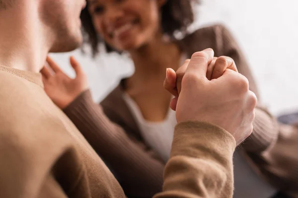 Blurred interracial couple holding hands at home — Stock Photo