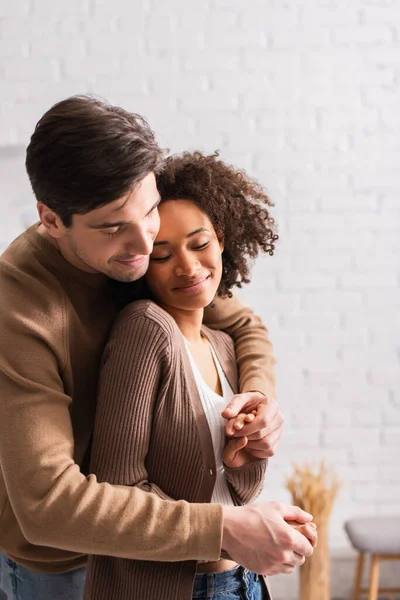 Hombre abrazando bastante africana americana novia en casa - foto de stock