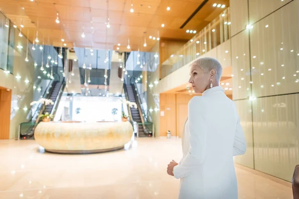 Reife und trendige Geschäftsfrau in der geräumigen Lobby eines Luxushotels — Stockfoto