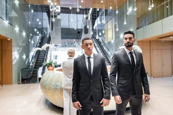 Multiethnic bodyguards protecting mature businesswoman standing at hotel reception — Stock Photo