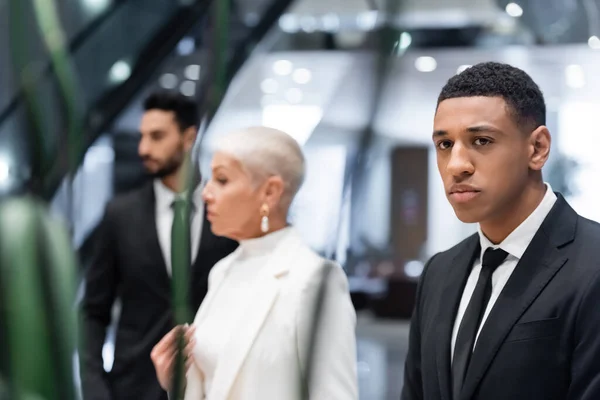 Foyer sélectif de l'homme de sécurité afro-américain près floue femme d'affaires avec garde du corps bi-raciale à l'hôtel — Photo de stock