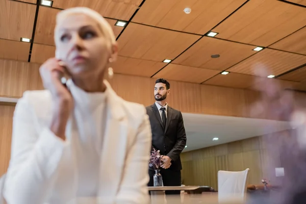 Selektiver Fokus des Sicherheitsmannes im Mixed Race in der Nähe einer älteren Geschäftsfrau auf verschwommenem Vordergrund — Stockfoto