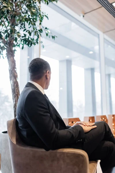 Afrikanisch-amerikanischer Mann im schwarzen Anzug sitzt in Hotellounge — Stockfoto