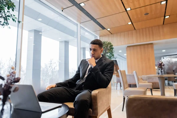 Cher garde afro-américain assis dans le salon de l'hôtel et regardant ordinateur portable — Photo de stock