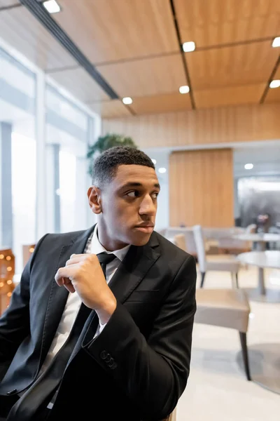 African american security man in black blazer looking away in hotel lounge — Stock Photo