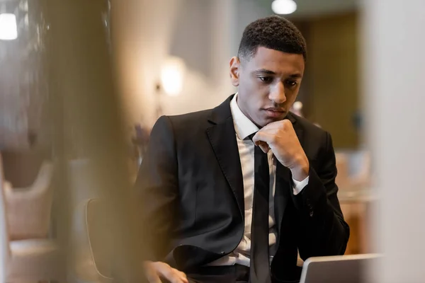 Pensativo guarda afro-americano sentado no salão do hotel em primeiro plano turvo — Fotografia de Stock