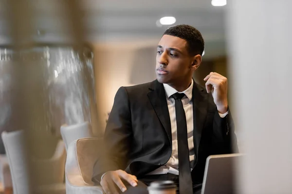 Thoughtful african american guard sitting in hotel lounge on blurred foreground — Stock Photo