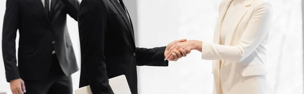 Partial view of business partners shaking hands near african american security man, banner — Stock Photo
