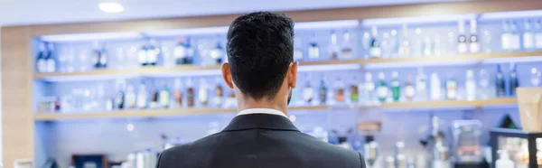 Vista trasera del hombre de seguridad cerca del bar borroso del hotel, pancarta - foto de stock