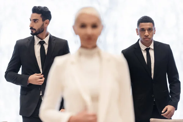 Interracial bodyguards in formal wear escorting blurred businesswoman during business trip — Stock Photo