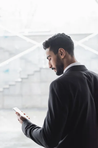 Jeune garde mixte de course regardant le téléphone mobile dans le lobby flou de l'hôtel — Photo de stock