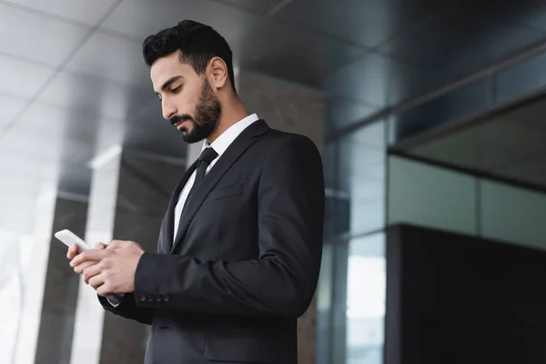 Garde bi-raciale en costume de messagerie sur téléphone mobile à l'extérieur — Photo de stock