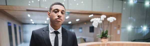 African american man in formal wear looking at camera in hotel lobby, banner — Stock Photo