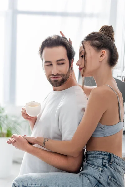 Tattooed young woman in bra and jeans holding hands with bearded boyfriend — Stock Photo