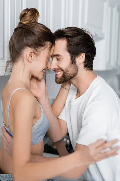 Feliz casal abraçando e sorrindo na cozinha — Fotografia de Stock