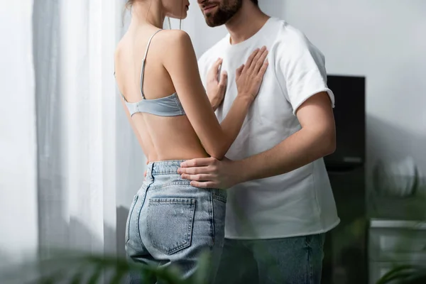 Cropped view of woman in bra and bearded man hugging at home — Stock Photo