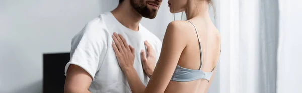 Cropped view of woman in bra and bearded man hugging at home, banner — Stock Photo