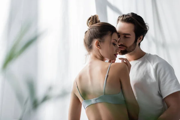 Sensual woman in bra near bearded man at home — Stock Photo