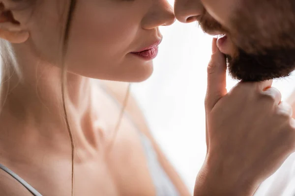 Vista recortada de la mujer con los ojos cerrados tocando el labio del hombre barbudo - foto de stock