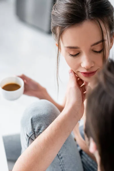 High angle view of blurred man touching face of girlfriend with cup of coffee — Stock Photo