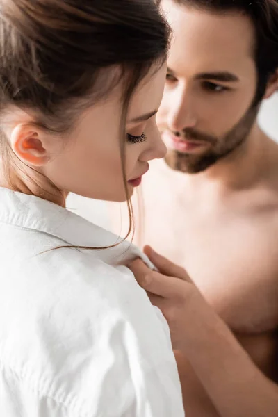 Desenfocado y sin camisa hombre seduciendo novia en camisa blanca - foto de stock