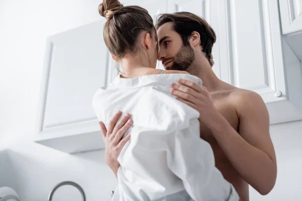 Low angle view of shirtless man undressing girlfriend in white shirt — Stock Photo
