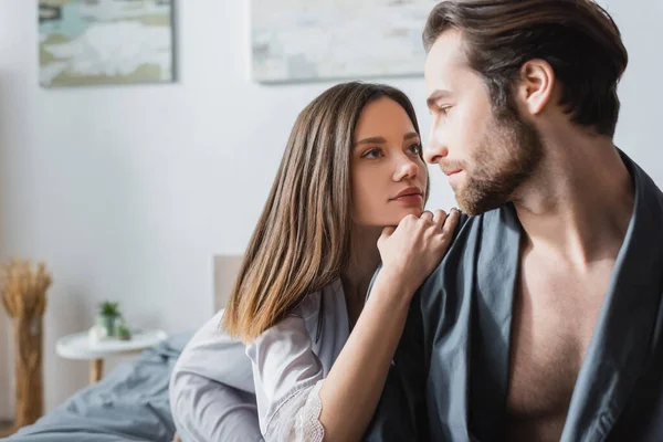 Mujer joven mirando al hombre barbudo en bata - foto de stock