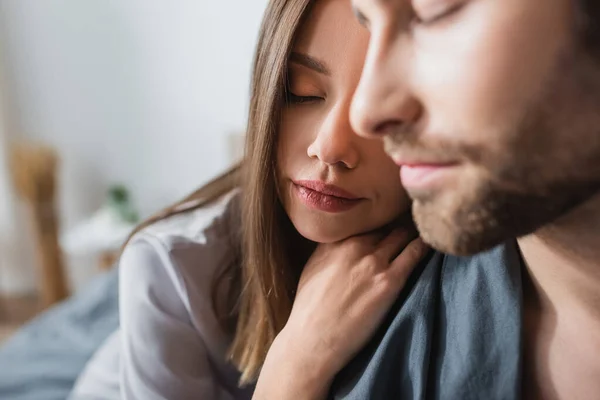 Donna sensuale in vestaglia di seta appoggiata sulla spalla dell'uomo barbuto sfocato — Foto stock