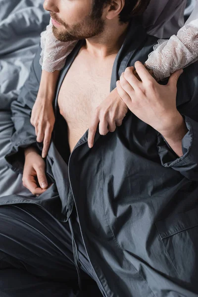 Обрезанный вид женщины обнимающей бородатого бойфренда в халате — стоковое фото