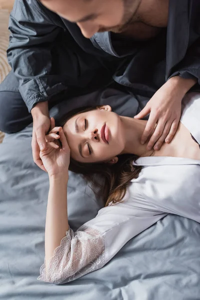 Vista superior de la joven mujer en bata de seda acostada en la cama cerca del hombre - foto de stock