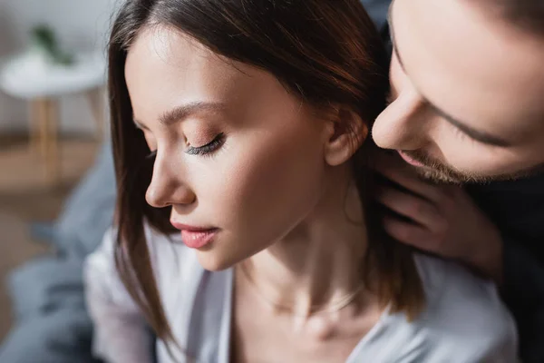 Primer plano de hombre barbudo seduciendo a mujer sensual en túnica de seda - foto de stock