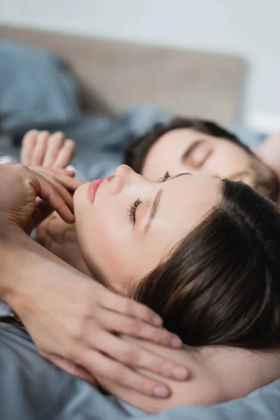 Mujer joven con los ojos cerrados acostado cerca de hombre borroso - foto de stock