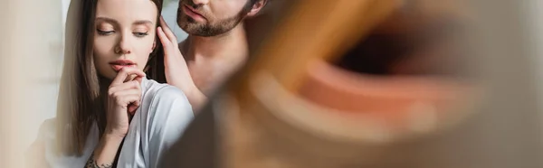 Hombre barbudo acariciando el pelo de la novia tatuada en bata de seda, bandera — Stock Photo