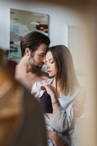 Shirtless man undressing tattooed woman in silk robe — Stock Photo