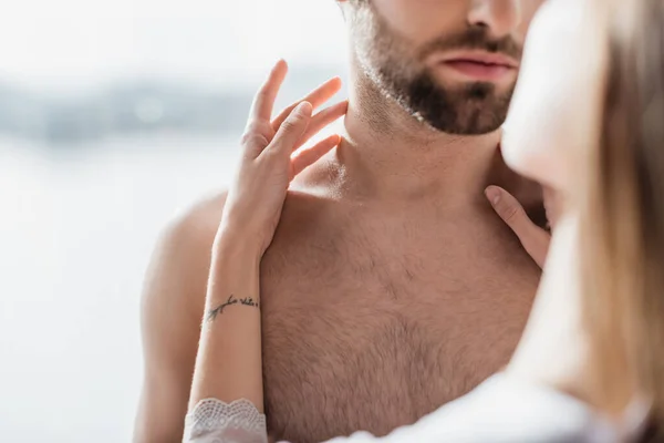 Teilbild einer tätowierten jungen Frau, die ihren hemdlosen Freund zu Hause umarmt — Stockfoto