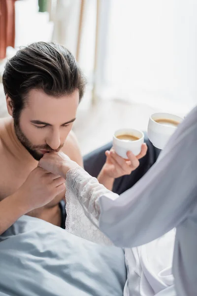 Bearded man kissing hand of girlfriend in silk robe — Stock Photo