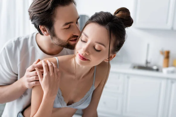 Bearded man embracing and whispering to young pretty woman in bra at home — Stock Photo