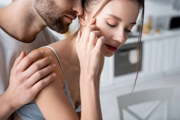 Bearded man hugging young pretty woman in bra at home — Stock Photo