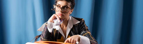 Pensive vintage style newswoman holding crumpled paper while looking away on blue background, banner — Stock Photo