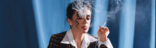 Brunetta donna in abiti vintage fumare su sfondo blu, banner — Foto stock