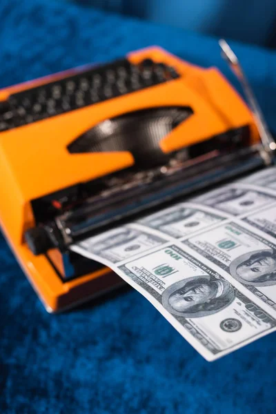 High angle view of blurred vintage typewriter and dollar banknotes on blue table — Stock Photo