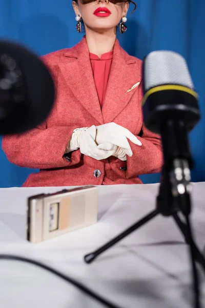 Micrófonos borrosos y grabadora de voz cerca de la mujer de estilo vintage recortado sobre fondo azul - foto de stock